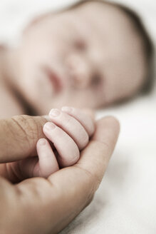 Vater hält die Hand seines schlafenden neugeborenen Sohnes - JATF000399