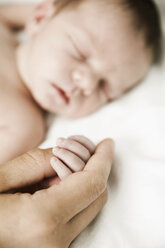 Father holding hand of his sleeping newborn son - JATF000400