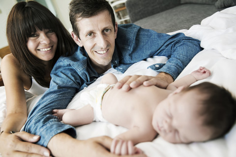 Glückliche junge Eltern mit ihrem neugeborenen Sohn zu Hause, lizenzfreies Stockfoto