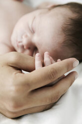 Mother holding hand of her sleeping newborn son - JATF000406