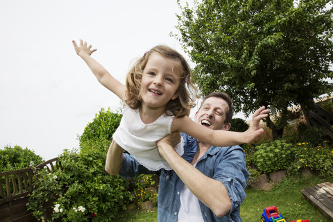 Vater spielt mit seiner kleinen Tochter im Garten, lizenzfreies Stockfoto