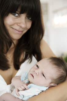 Lächelnde junge Mutter, die ihren neugeborenen Sohn in den Armen hält - JATF000423