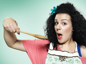 Portrait of astonished young woman with wooden spoon, studio shot - STKF000395