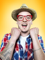 Porträt eines glücklichen jungen Mannes mit roter Brille und Hut, Studioaufnahme - STKF000398
