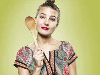 Portrait of young woman holding wooden spoon, studio shot - STKF000403