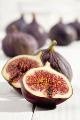 Sliced and whole figs on white wooden table, studio shot - CSF020194
