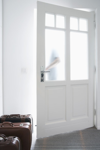 Germany, Cologne, Man behind door, packed luggage in entrance stock photo