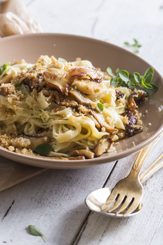 Tagliatelle mit gelben Steinpilzen und Semmelbröseln, Parmesan und Oregano auf Teller, lizenzfreies Stockfoto