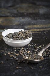 Swabian lentils (Alb Leisa lentils) in small white bowl and a spoon on dark surface, close-up - SBDF000272