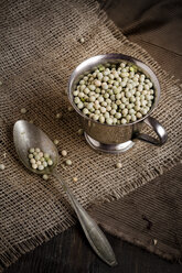 Dried green peas in a metal cup with spoon on jute fabric, studio shot - SBDF000279