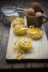 Uncooked tagliatelle and eggs on wooden table - LVF000249