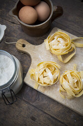 Uncooked tagliatelle and eggs on wooden table - LVF000247