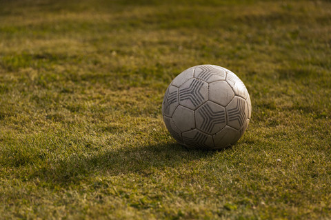 Old football on grass, close-up stock photo