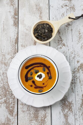 Pumpkin soup in old bowl garnished with pumpkin seed oil, studio shot - CSF020269