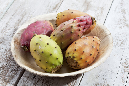 Kaktusfeigen (Opuntia ficus-indica) auf Teller aus Palmblättern auf weißem Holztisch, Studioaufnahme - CSF020291