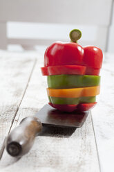 Mix of sliced sweet peppers (Capsicum) from different colours stacked on chopping knife, studio shot - CSF020292