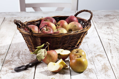 Bio-Äpfel (Malus), Korb und ein Messer auf weißem Holztisch, Studioaufnahme - CSF020300