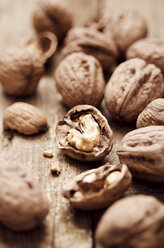 Walnuts with shell, one without, on wooden table, close-up - CZF000099