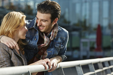 Germany, Dusseldorf, Young couple embracing, leaning on railing - STKF000423