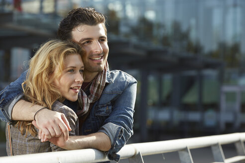 Germany, Dusseldorf, Young couple embracing, leaning on railing - STKF000425