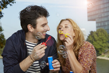 Germany, Dusseldorf, Young couple making soap bubbles - STKF000438