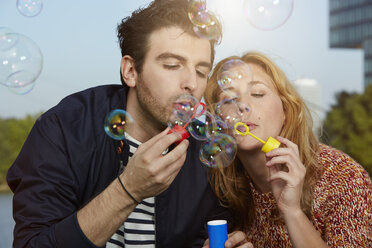 Germany, Dusseldorf, Young couple making soap bubbles - STKF000439