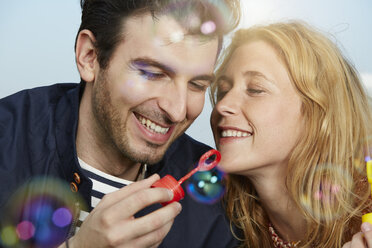 Germany, Dusseldorf, Young couple making soap bubbles - STKF000440