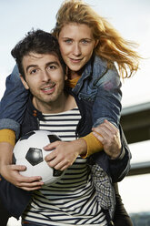 Germany, Dusseldorf, Young couple playing football - STKF000456