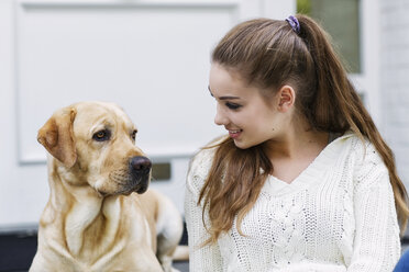 Teenager-Mädchen mit Hund vor einer Eingangstür sitzend - GDF000283