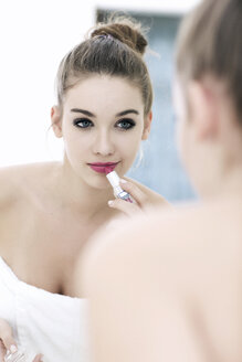 Porträt eines Teenagers, der Lippenstift aufträgt, während er sein Spiegelbild betrachtet - GDF000256