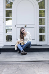 Teenager-Mädchen mit Hund vor einer Eingangstür sitzend - GDF000284
