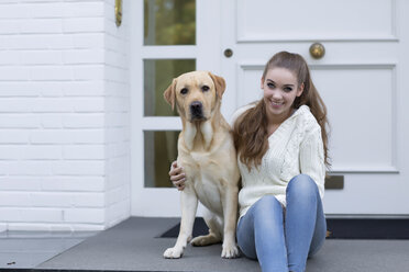 Teenager-Mädchen mit Hund vor einer Eingangstür sitzend - GDF000285