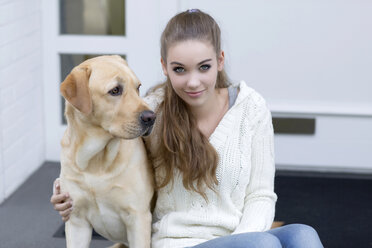 Teenager-Mädchen mit Hund vor einer Eingangstür sitzend - GDF000286