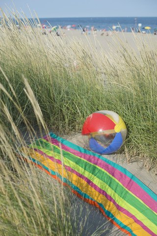 Italien, Adria, Strandball und Handtuch auf Sanddüne mit Gras, lizenzfreies Stockfoto