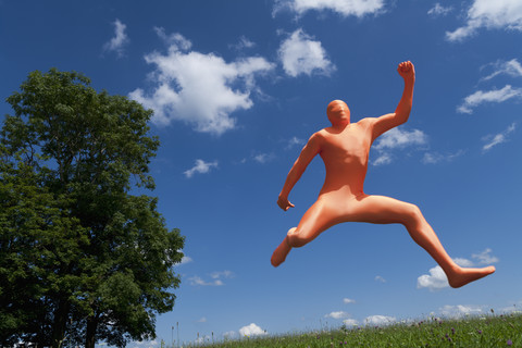 Deutschland, Bayern, Mann in orangefarbenem Zentai springt in Landschaft, lizenzfreies Stockfoto