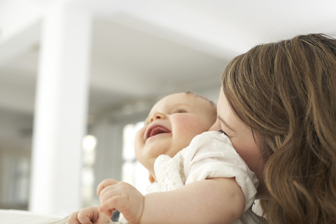 Mother kissing her laughing baby girl stock photo