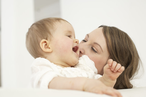 Mother kissing her smiling baby girl stock photo