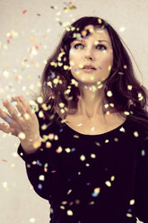 Young woman looking at confetti in the air - NGF000048