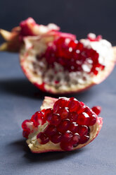 Two pieces of pomegranate [Punica granatum] on blue wood, studio shot - MYF000056