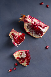 Pits and three pieces of pomegranate [Punica granatum] on blue wood, studio shot - MYF000057