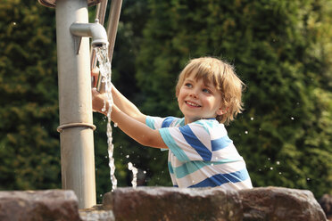 Porträt eines kleinen Jungen, der mit einer Wasserpumpe spielt - RDF001197