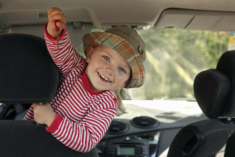 Kleiner Junge zeigt Schraubenzieher im Auto, lizenzfreies Stockfoto