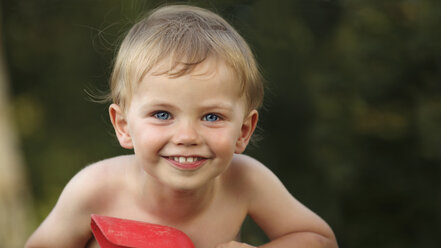 Porträt eines lächelnden kleinen Jungen, der mit einer Schaufel spielt - RDF001205
