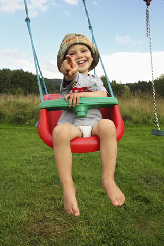 Kleiner Junge schaukelt im Garten, lizenzfreies Stockfoto