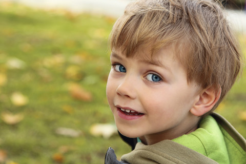 Portrait of smiling little boy looking over his shoulder stock photo