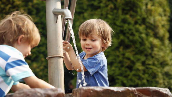 Zwei kleine Jungen spielen mit einer Wasserpumpe - RDF001231