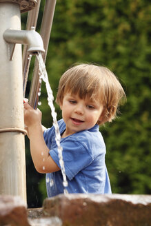Porträt eines kleinen Jungen, der mit einer Wasserpumpe spielt - RDF001232