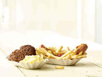 Currywurst mit Pommes frites, zwei Frikadellen und Kartoffelpüree auf Holztisch - SRSF000313