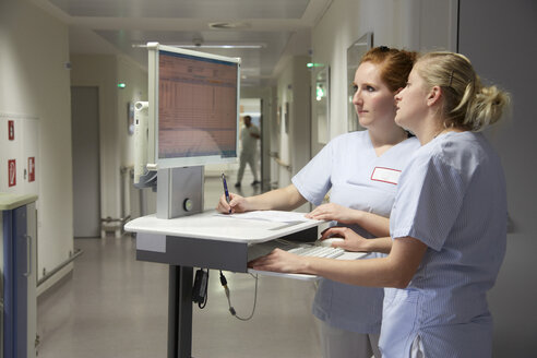 Germany, Freiburg, Nurses with mobile computer deskte, checking patient data - DHL000147