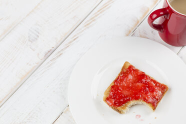 Angebissenes Toastbrot mit roter Marmelade auf Teller, Studioaufnahme - DRF000268